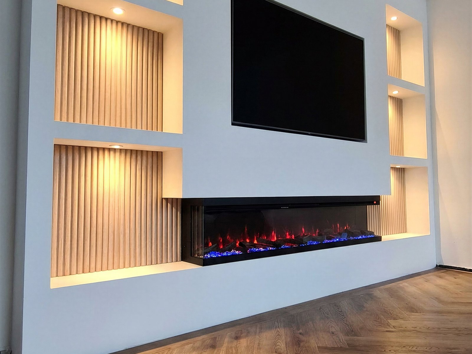 3D sfeerhaard driezijdig ingebouwd in een tv wand met verlichte nissen van houten latten, vlam zichtbaar van voren en opzij