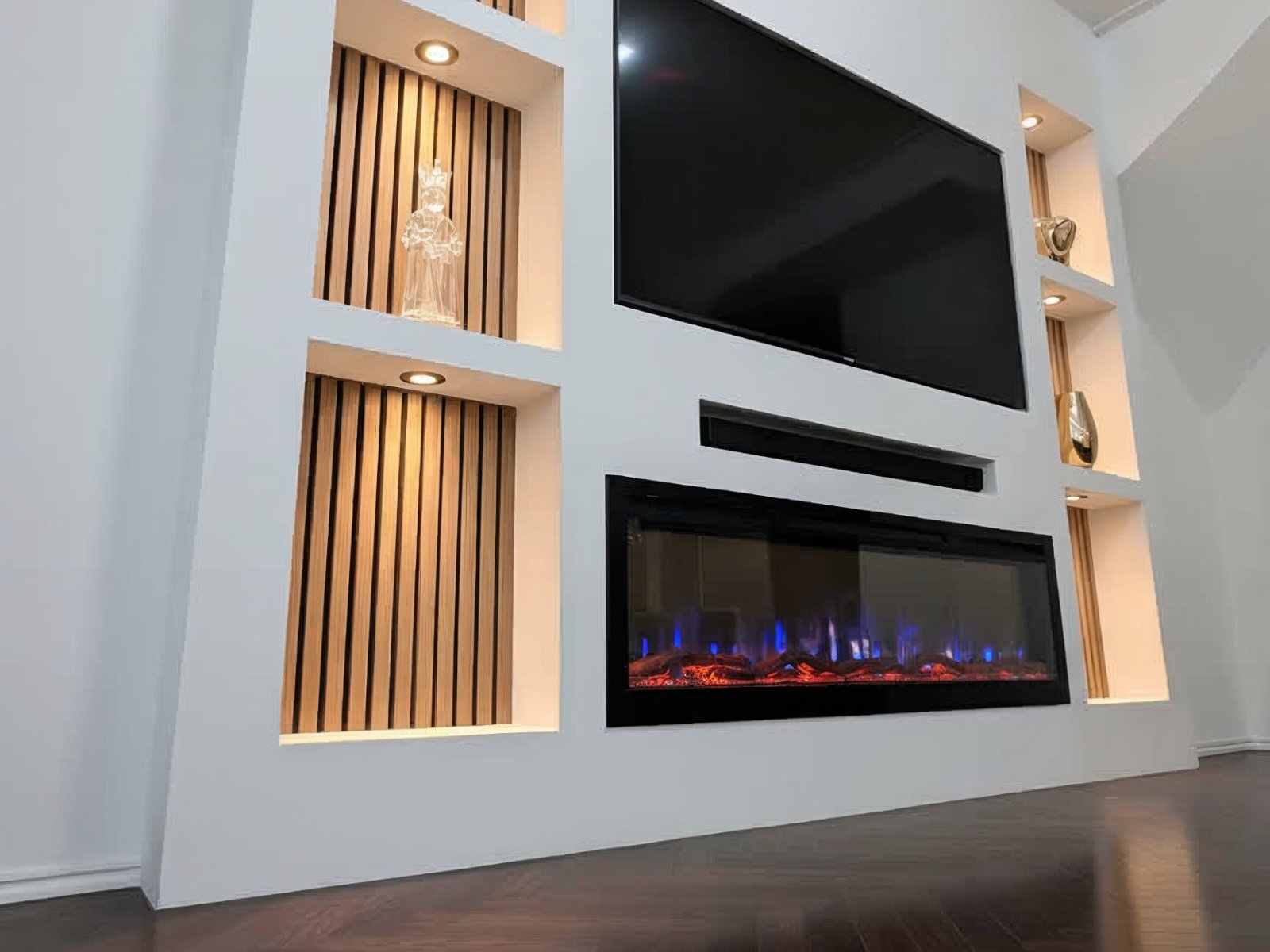 Cinewall met haard en opbergruimte: verlichte nissen met houten latten naast de tv, met de elektrische haard eronder