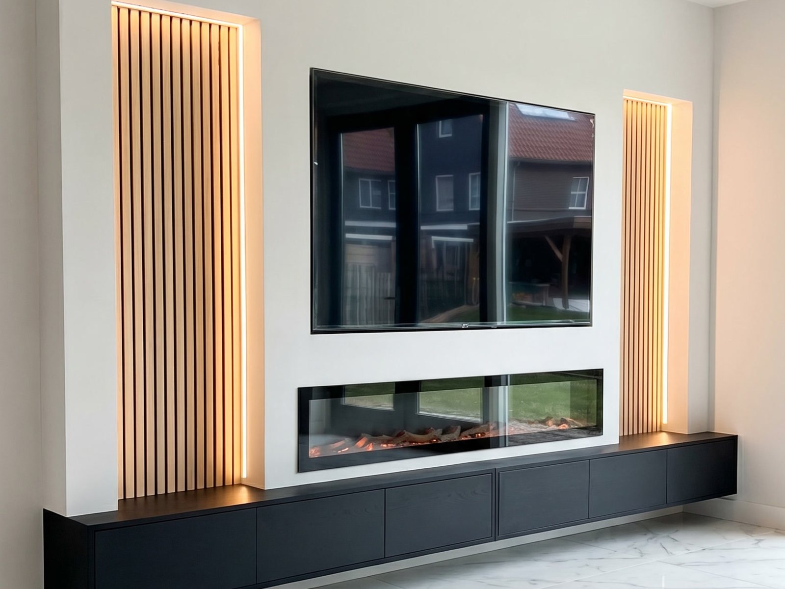 Tv wand idee: zwevende cinewall met verlichte houten lamellen, verzonken tv, brede elektrische haard en zwart zwevend tv-meubel